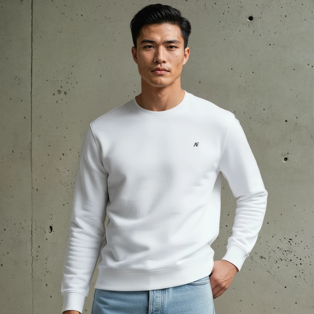 Man wearing a white Helios Crew sweater and light blue jeans against a gray concrete wall